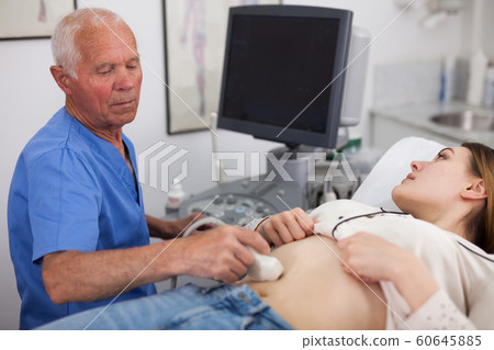Elderly male sonographer examining woman Elderly male sonographer examining woman 60645885