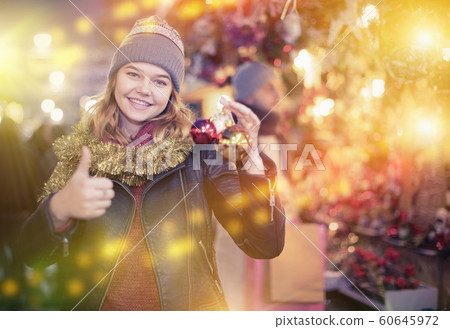 Smiling girl choosing decorations at Christmas market Smiling girl choosing decorations at Christmas market 60645972