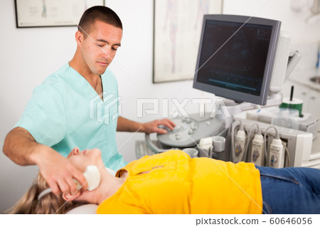 Man doctor conducting ultrasound examination of patient's thyroid lying Man doctor conducting ultrasound examination of patient's thyroid lying 60646056
