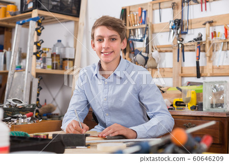 teenager smiling and working with wood in the workshop 60646209