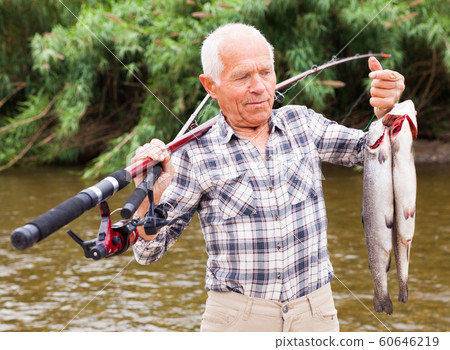 Mature fisherman examining catch Mature fisherman examining catch 60646219