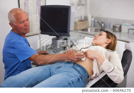 Elderly male sonographer examining woman 60646270