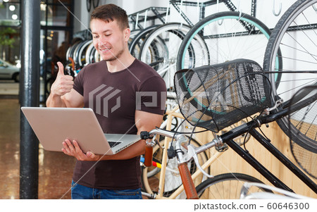 Smiling man is shopping and choosing new bicycle with notebook Smiling man is shopping and choosing new bicycle with notebook 60646300
