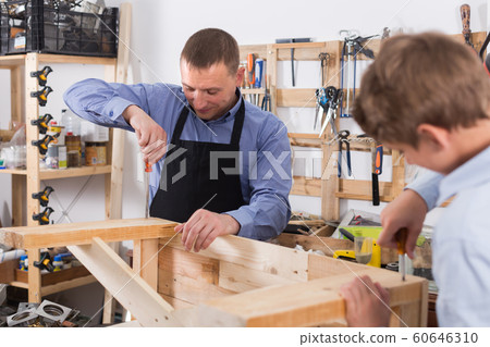 teacher and boy chiselling a wooden bench in workshop teacher and boy chiselling a wooden bench in workshop 60646310