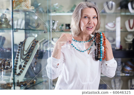 Adult woman chooses jewelry from turquoise jewelery in the store Adult woman chooses jewelry from turquoise jewelery in the store 60646325