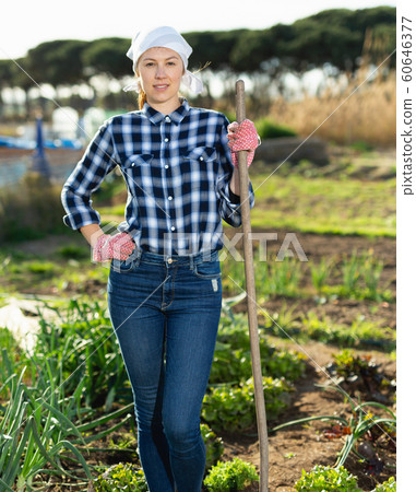 Positive farmer girl with rake in garden beds Positive farmer girl with rake in garden beds 60646377