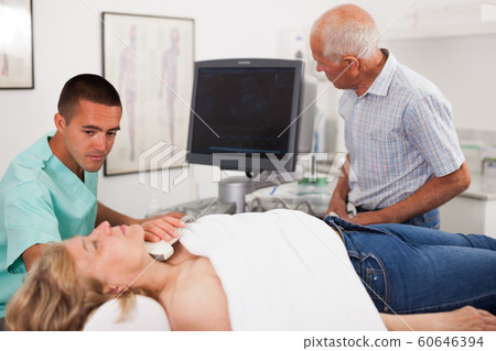 Doctor conducting ultrasound examination of patient's thyroid lying Doctor conducting ultrasound examination of patient's thyroid lying 60646394