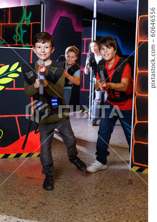 Emotional teen boy with laser pistol playing laser tag with friends on dark labyrinth Emotional teen boy with laser pistol playing laser tag with friends on dark labyrinth 60646556
