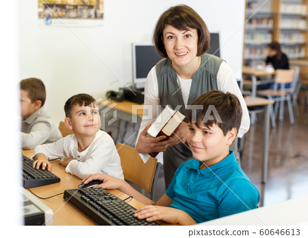 Female teacher working with pupil in computer class 60646613