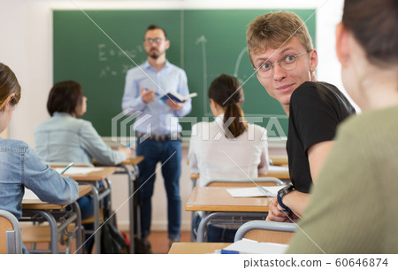 Smiling teenagers are talking about homework at the desk in time lecture 60646874
