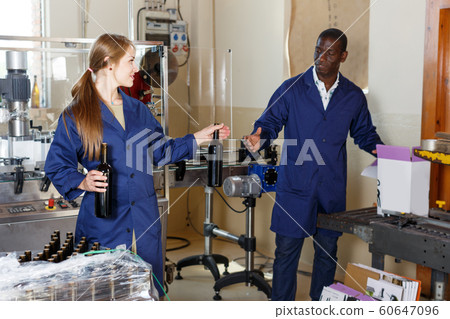 Woman and man winemakers packing bottles with wine in box at winery production 60647096