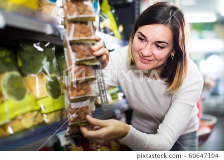 smiling girl customer looking for tasty snacks in supermarket smiling girl customer looking for tasty snacks in supermarket 60647104