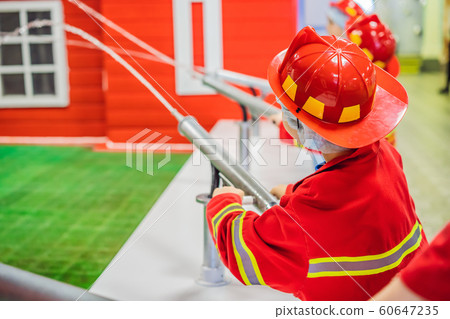 Expressive cute toddler with fireman's outfit playing fireman Expressive cute toddler with fireman's outfit playing fireman 60647235