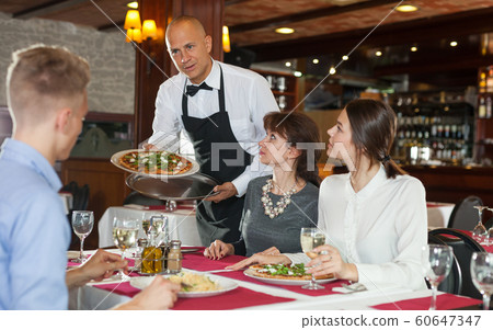 Waiter serving pizza to visitors Waiter serving pizza to visitors 60647347