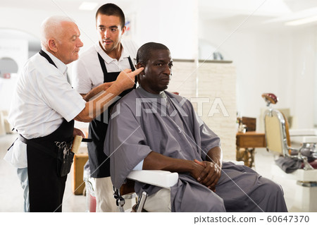 Aged barber teaching apprentice to male haircut Aged barber teaching apprentice to male haircut 60647370