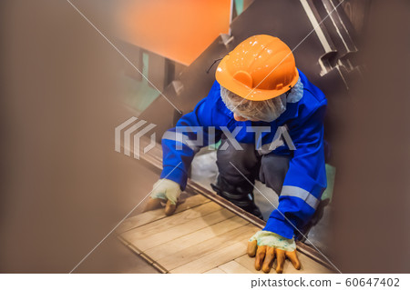 Boy plays in a children s construction site. Stacking parquet Boy plays in a children s construction site. Stacking parquet 60647402