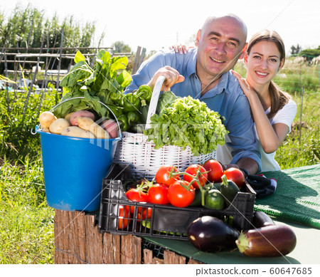 Happy family of gardeners posing with harvest of vegetables and greens Happy family of gardeners posing with harvest of vegetables and greens 60647685
