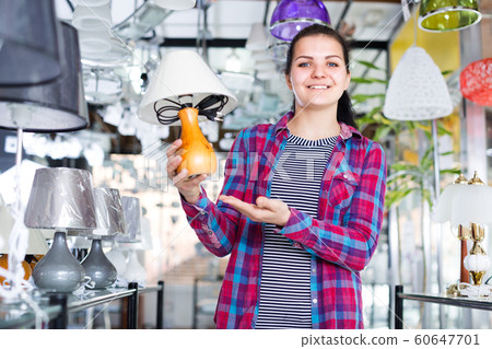 Girl in lighter shop is choosing stylish and modern lamp 60647701