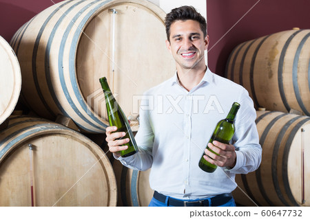 Cheerful man customer having bottle of wine in shop Cheerful man customer having bottle of wine in shop 60647732