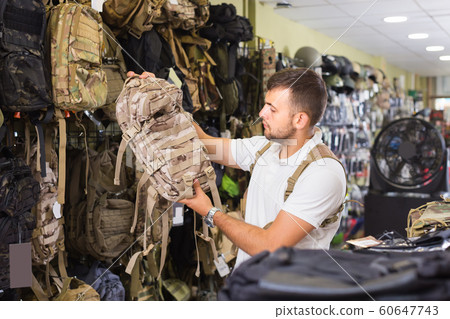 Man choosing textile backpack gun in military shop Man choosing textile backpack gun in military shop 60647743