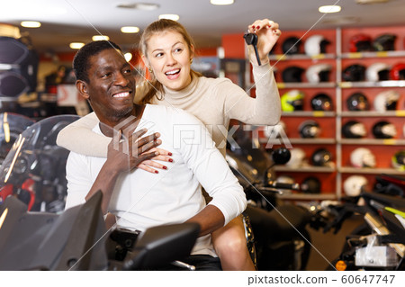 glad man and woman posing on new motorcycle in shop glad man and woman posing on new motorcycle in shop 60647747