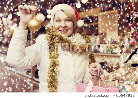 Adult woman is choosing decorations for Christmas tree in the market Adult woman is choosing decorations for Christmas tree in the market 60647938
