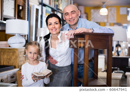 Family is holding new curbstone that their choosing for bedroom in the furniture store. 60647941