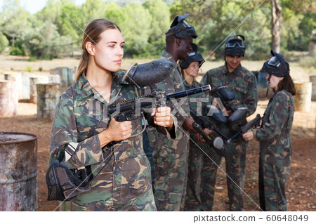 Woman paintball player standing with gun 60648049