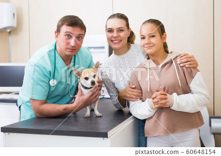 Cheerful mother and daughter visiting veterinarian clinic with their puppy 60648154