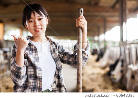 Portrait of chinese female farmer who is standing at her workplace near cows at the farm outdoors 60648385