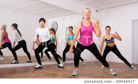 Cheerful different ages women learning swing steps at dance class Cheerful different ages women learning swing steps at dance class 60648417