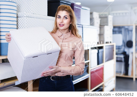Pretty saleswoman offering soft pouf in store Pretty saleswoman offering soft pouf in store 60648452