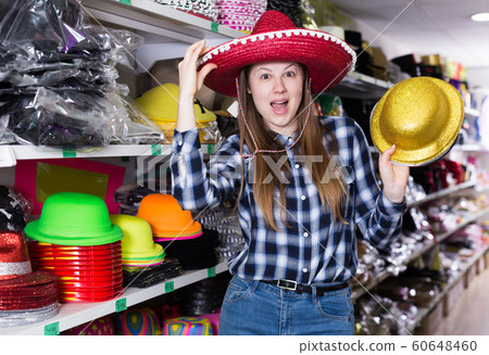Girl trying on party hats in shop Girl trying on party hats in shop 60648460