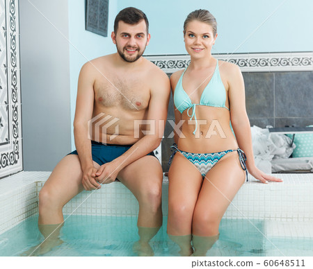 couple sitting at edge of pool in spa center couple sitting at edge of pool in spa center 60648511