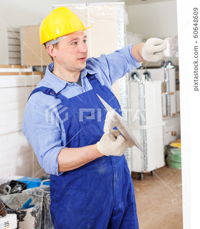 Construction worker plastering wall 60648609