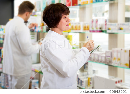 Pharmacist and pharmacy technician posing in drugstore Pharmacist and pharmacy technician posing in drugstore 60648901