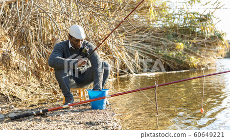 Positive fisherman sitting near river 60649221