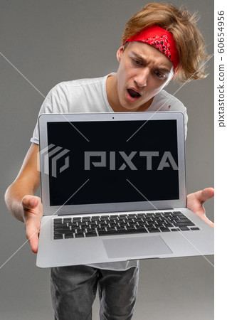 european stylish guy shows a laptop screen with a mockup on a gray background european stylish guy shows a laptop screen with a mockup on a gray background 60654956
