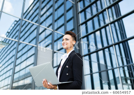 Caucasian woman in office clothes do freelance with laptop and waits colleague near the office Caucasian woman in office clothes do freelance with laptop and waits colleague near the office 60654957