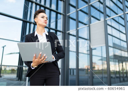 Caucasian woman in office clothes do freelance with laptop and waits colleague near the office 60654961