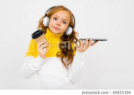 Beautiful teenager caucasian girl listen to music with big earphones and drinks coffee isolated on Beautiful teenager caucasian girl listen to music with big earphones and drinks coffee isolated on 60655394