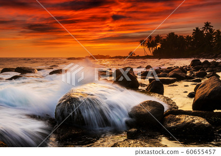 Sunset on the rocky shore of tropical sea 60655457