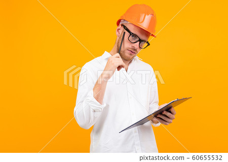 Beautiful caucasian engineer man with glasses and orange helmet isolated on yellow background 60655532