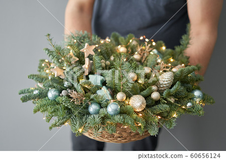 Big arrangement of fresh spruce in a wicker basket. Christmas mood. Beautiful bouquet in womans hands.. Big arrangement of fresh spruce in a wicker basket. Christmas mood. Beautiful bouquet in womans hands.. 60656124