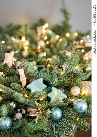 Big arrangement of fresh spruce in a wicker basket. Decorated with blue balls, cones and small stars. Christmas mood. light bulbs Garlands Big arrangement of fresh spruce in a wicker basket. Decorated with blue balls, cones and small stars. Christmas mood. light bulbs Garlands 60656125
