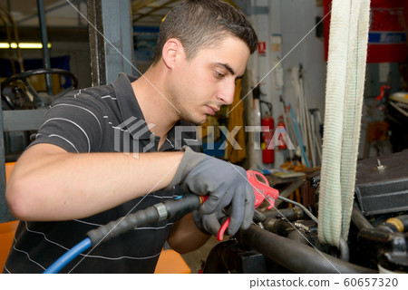 The mechanic cleans the engine with compressed air The mechanic cleans the engine with compressed air 60657320