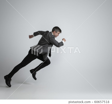 Caucasian man in office clothes running isolated on grey studio background 60657518