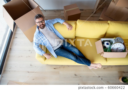 Top view of mature man with boxes moving in new house, relaxing on sofa. Top view of mature man with boxes moving in new house, relaxing on sofa. 60660422