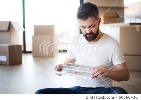 Mature man with boxes moving in new house, looking at color swatch. Mature man with boxes moving in new house, looking at color swatch. 60660430