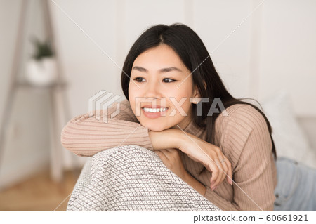 Cute asian girl resting on couch at home and smiling 60661921